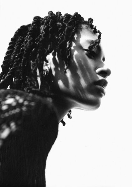 A close up of Annahstasia shot from below. Her hair is braided and we see her in profile. The black and white filter gives it a heavy contrast.